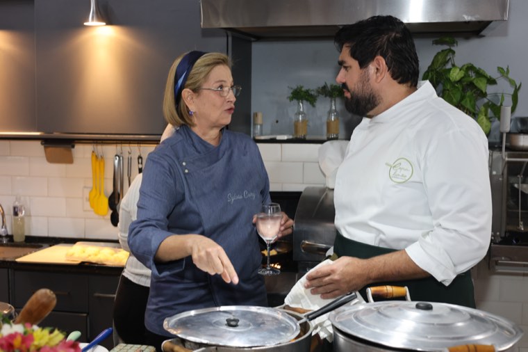 Sylvia Cury na cozinha, ao lado do cozinheiro que ajudou no serviço